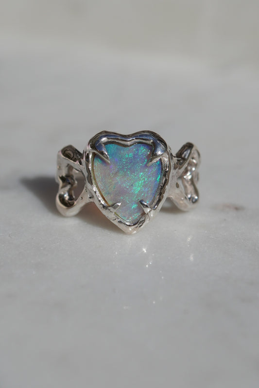Opal heart shaped ring set in silver, grey background